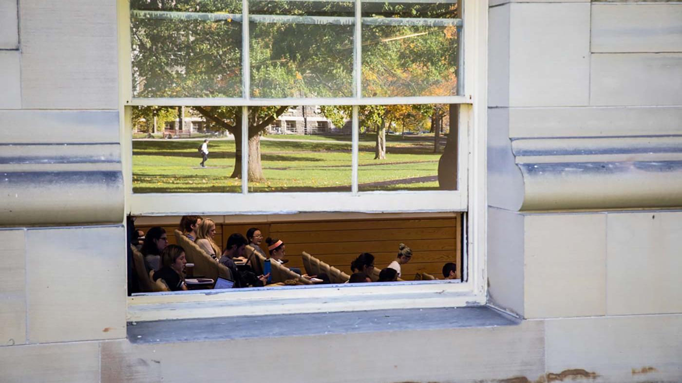 A classroom in Goldwin Smith Hall with the Arts Quad reflected in a window