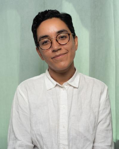 Headshot of MFA poetry student Aishvarya Arora wearing glasses and a white button-up shirt
