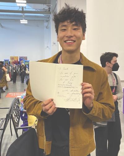 MFA student Derek Chan (poetry) displays their copy of "Burying the Mountain" by Shangyang Fang, freshly autographed by the author