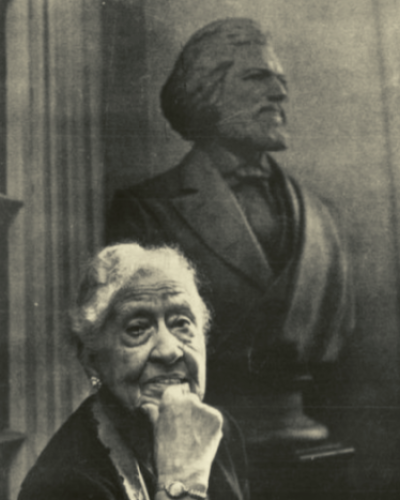 black and white photo of Mary Church Terrell seated before a bust of Frederick Douglass